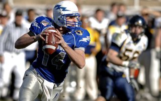 American football quarterback holding a ball and preparing for his next move - Tendo Sport