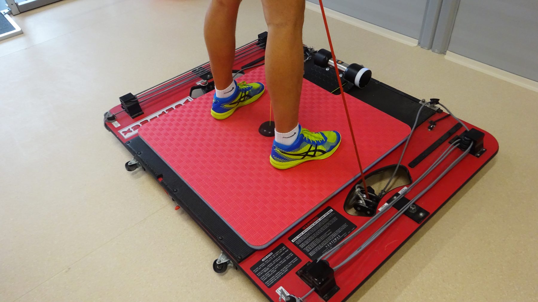 Male athlete performing jumps with Vertimax. Measuring power and velocity of legs using Tendo Unit and Tendo JumpMat with closeup on the mat